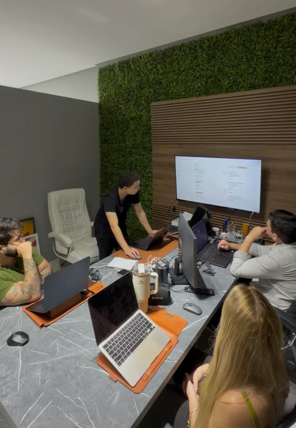 O time da Synar reunido em volta da mesa, acompanhando um projeto na tela